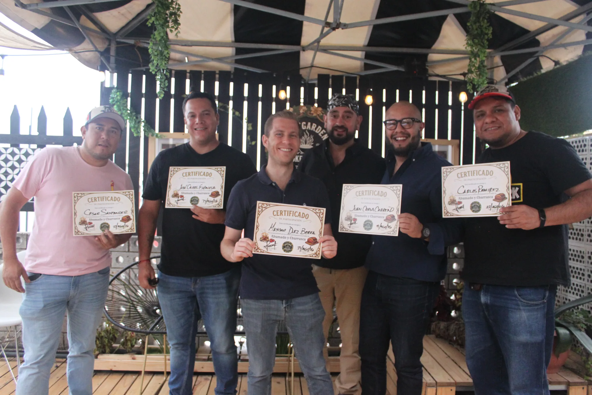 Alumnos de RoofGarden sonriendo y sosteniendo su certificado de participación del taller de Ahumado y Churrasca
