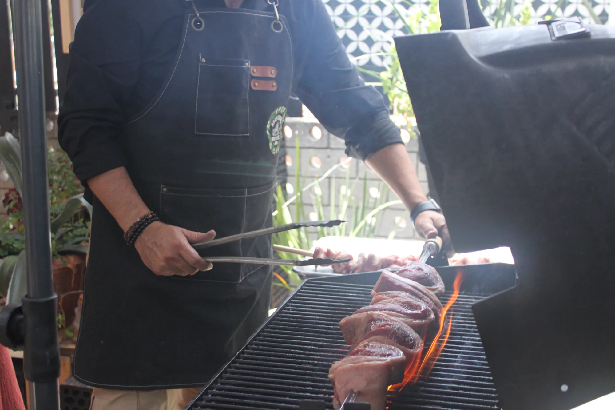 Chef girando un corte de carne sobre brasa viva durante el curso de Asado a la Leña