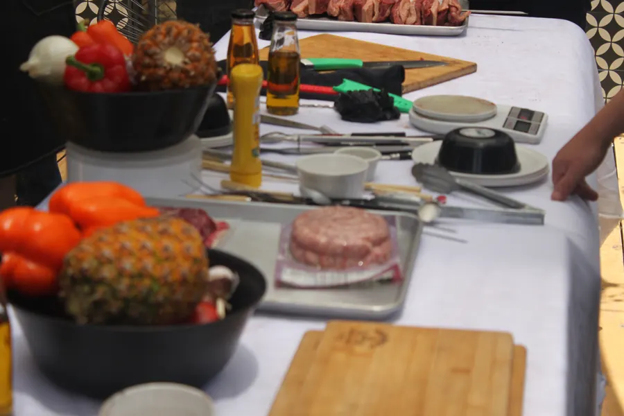Mesa de preparación con piña, pimientos, especias y herramientas de asador