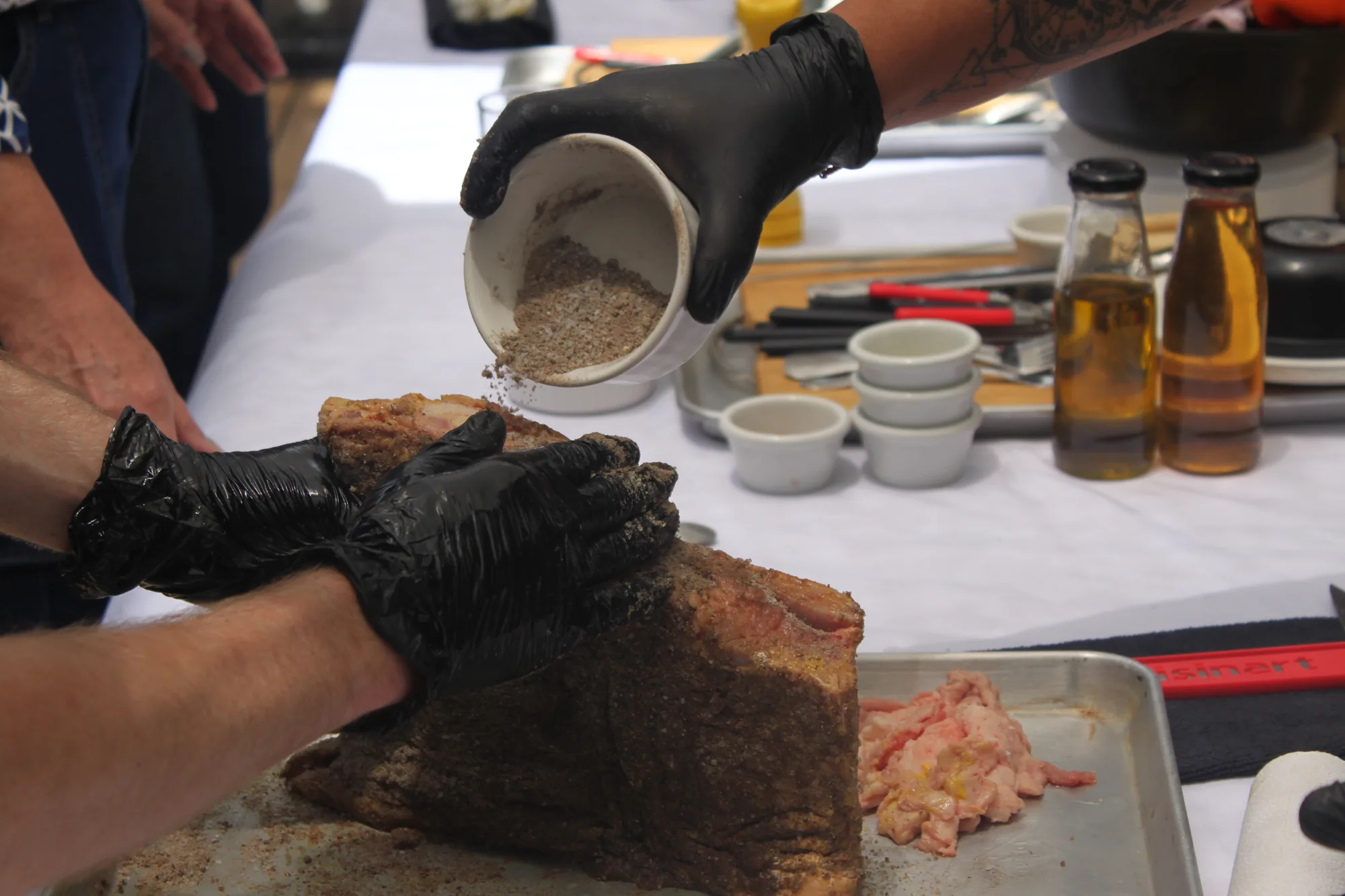 Manos aplicando rub de especias sobre una pieza de carne para el curso de Ahumado Lento